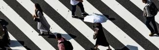 A picture of a crosswalk with many people walking across it